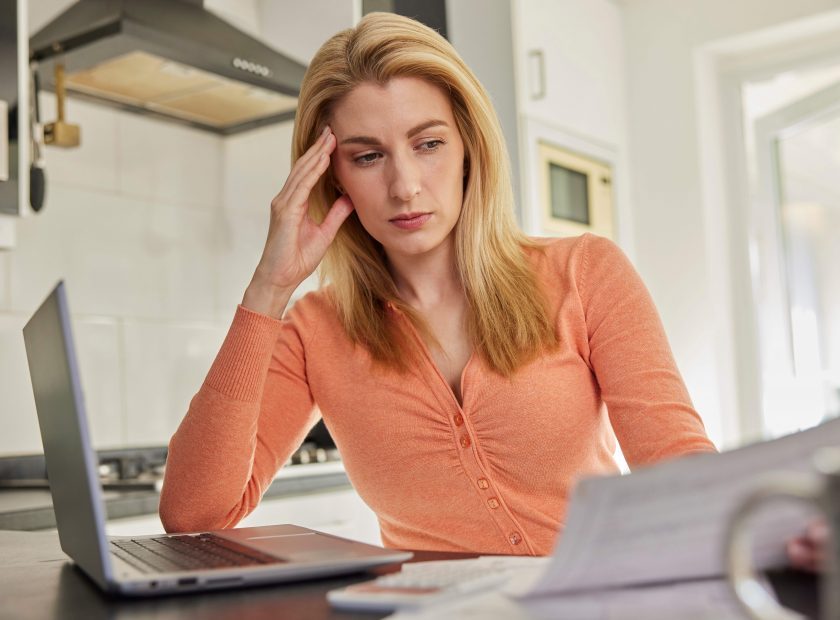 Woman,With,Laptop,At,Home,Looking,Worried,About,Household,Bills