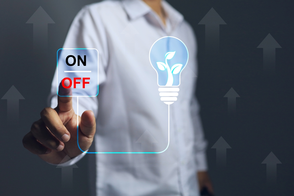 Hands turn off the light switch to save energy and costs reduce resource consumption